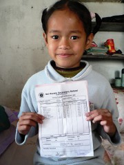 Nepálská dívka ukazuje své vysvědčení. Studovat může díky podpoře českého dárce.