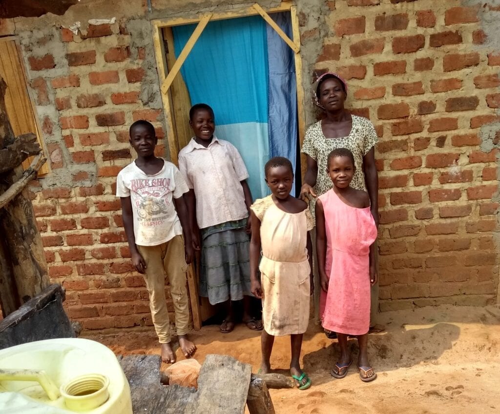 Čtyři děti a matka před cihlovým domkem.