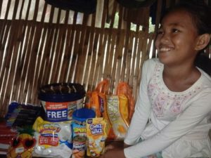 Dívenka se raduje z potravin, které si díky podpoře dárců může kupovat.
