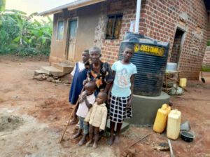 Babička Perepetua pózuje s dětmi, o které se stará, u nové nádrže na dešťovou vodu.